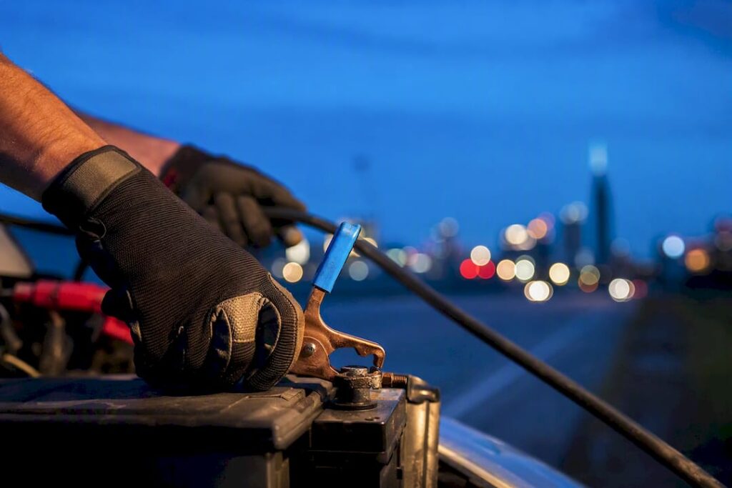Technician connecting booster cables roadside